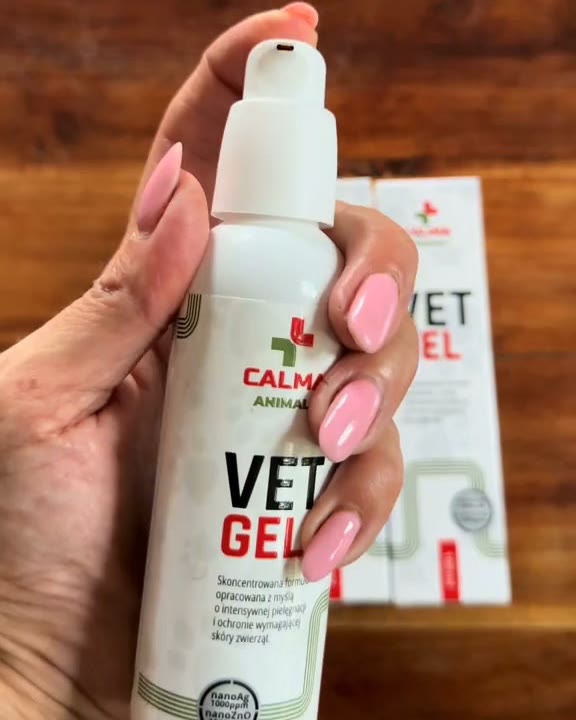 Dłoń trzyma butelkę VET GEL, w tle pudełka